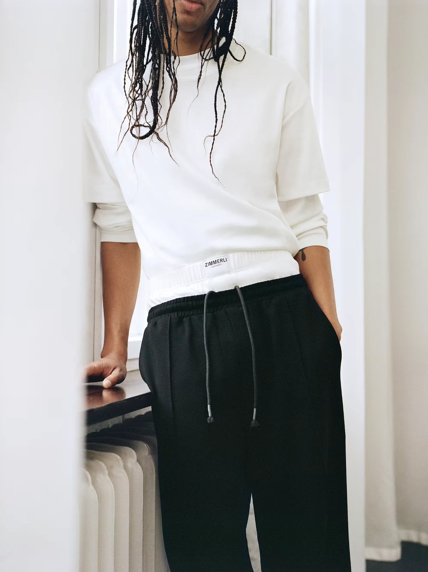 Highsnobiety editorial: model in white sweatshirt and black trousers